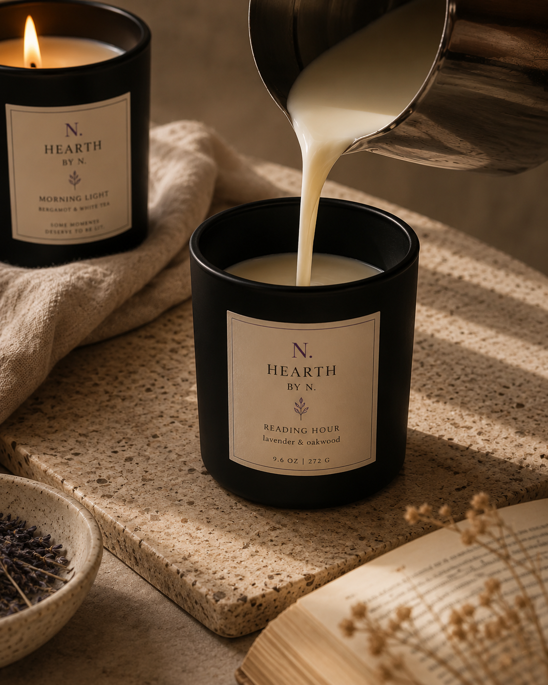 Cream soy wax being poured into an amber frosted HEARTH by N candle vessel on a travertine surface